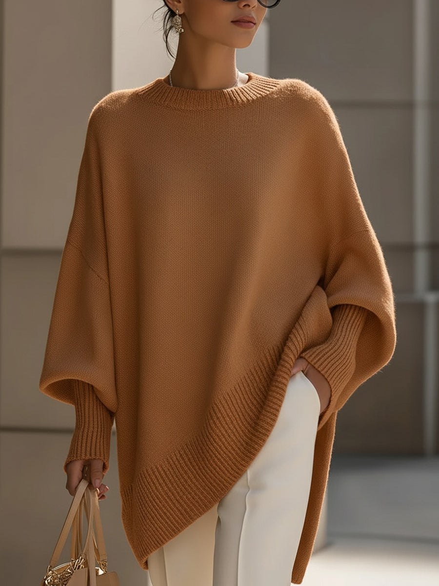 Chic women's oversized poncho sweater styled for autumn, perfect with jeans for elegant layering.