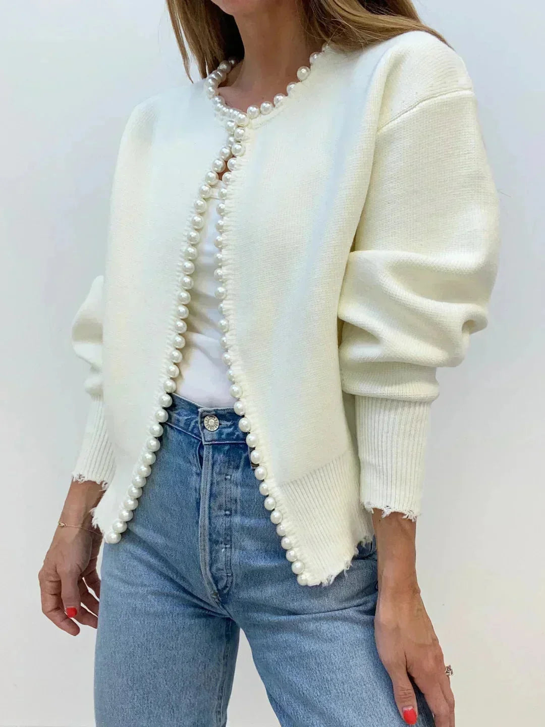 Close-up of elegant women's cardigan sweater with delicate pearl trim, highlighting classic fashion.