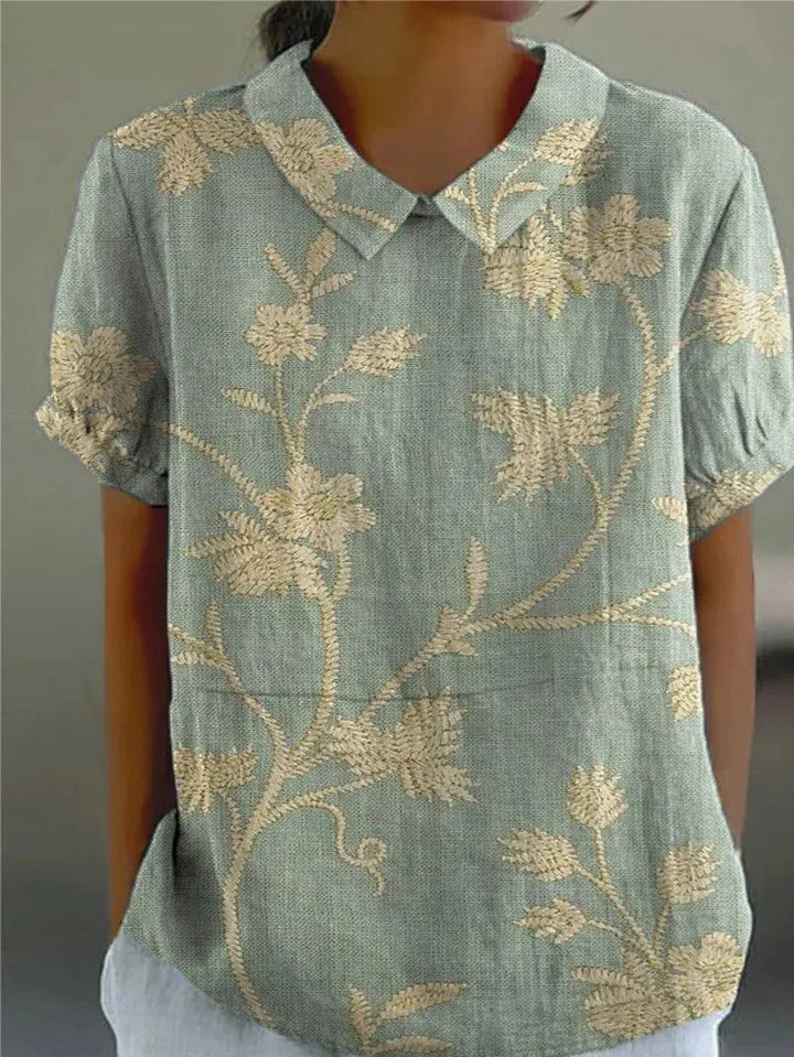 Women's embroidered floral blouse with Peter Pan collar & short sleeves. Elegant summer top.