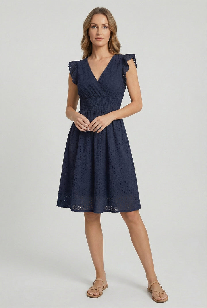 Full shot of a woman wearing a comfortable flared eyelet midi dress with chic ruffled sleeves.