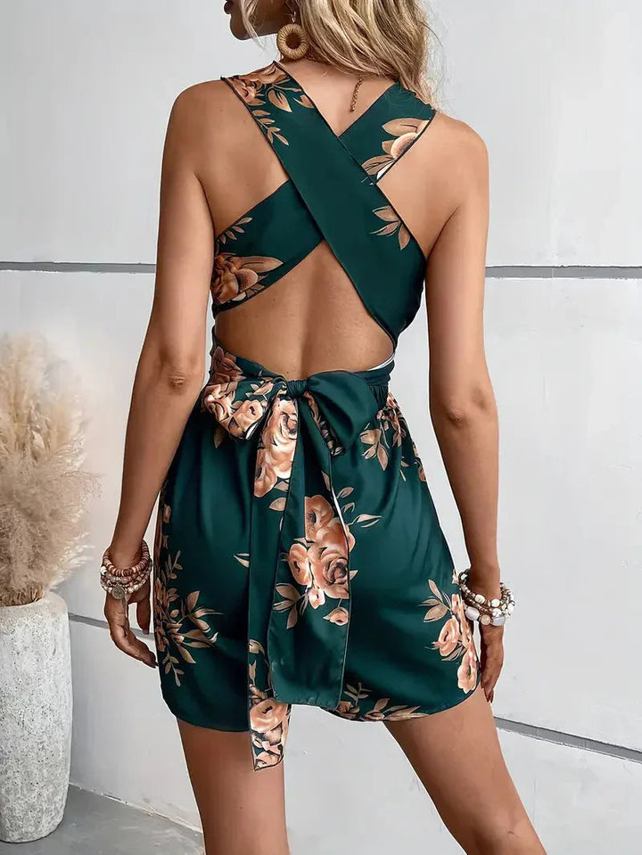 Breezy floral summer romper dress for women. Features an open back, halter neckline, & mini length.