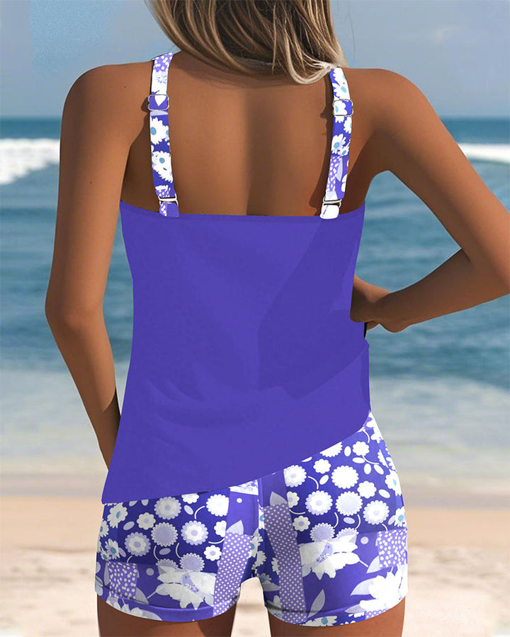 Woman enjoying beach in a vibrant floral print racerback tankini swimsuit set. Great summer beachwear.