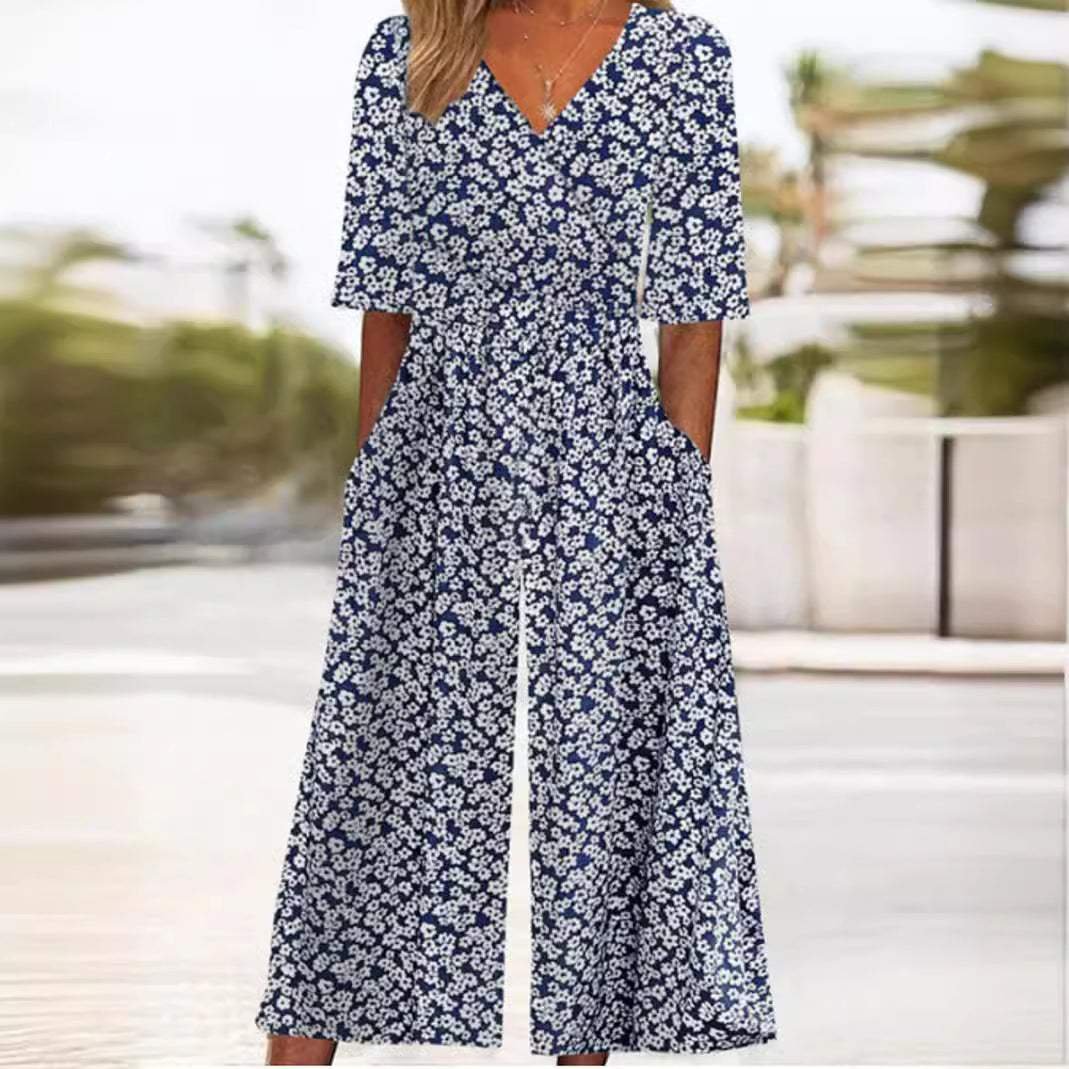 Navy blue floral wide-leg V-neck jumpsuit with elbow sleeves. Bohemian palazzo style for comfortable women's vacation wear.