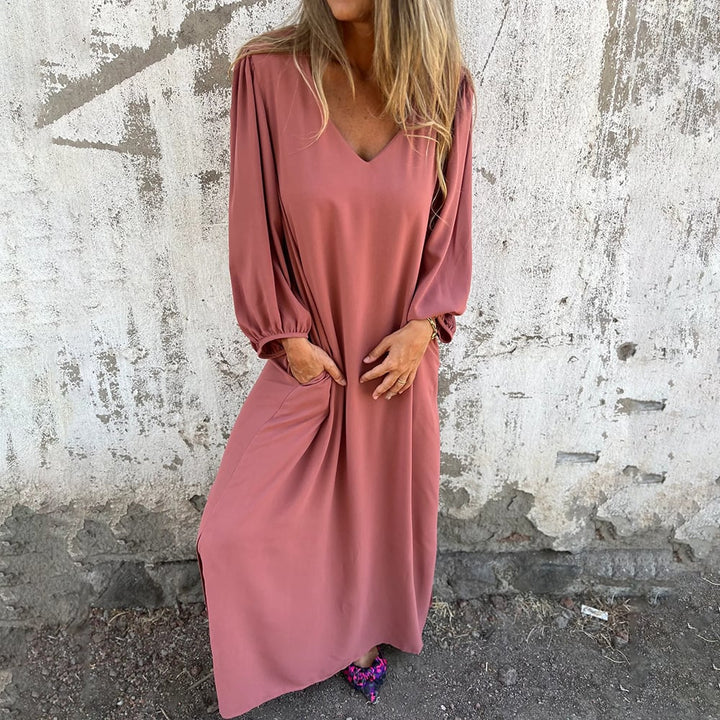 Woman wearing a comfortable flowy maxi dress with balloon sleeves and pockets, suitable for day or evening wear.