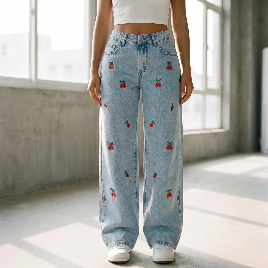 Women's high-waisted wide-leg light wash jeans with playful cherry embroidery. Relaxed fit denim.