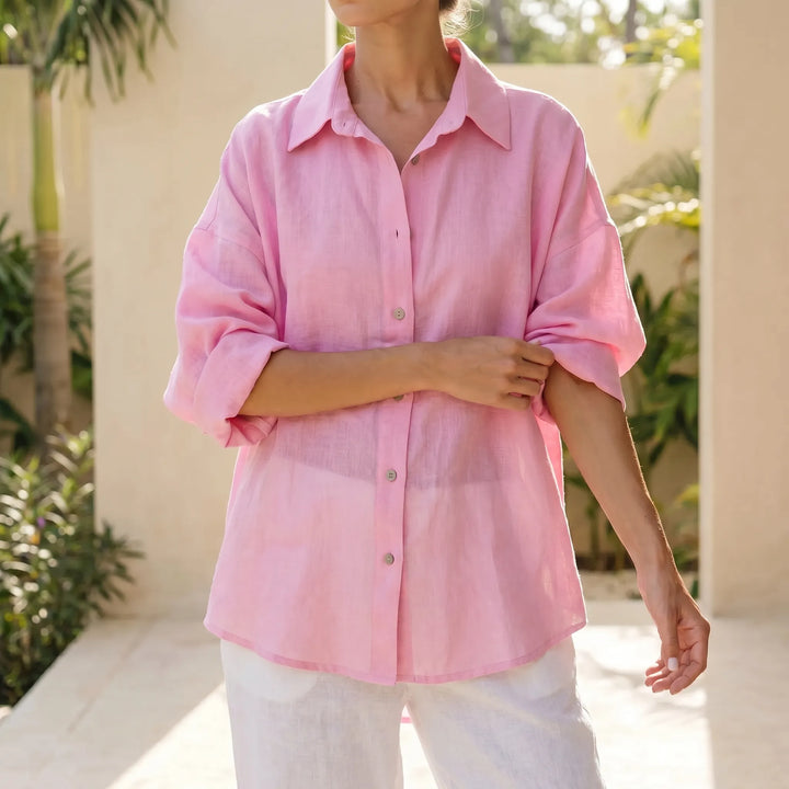Women's oversized button-down shirt in white, styled for a relaxed, casual summer look. Loose fit, long sleeves.