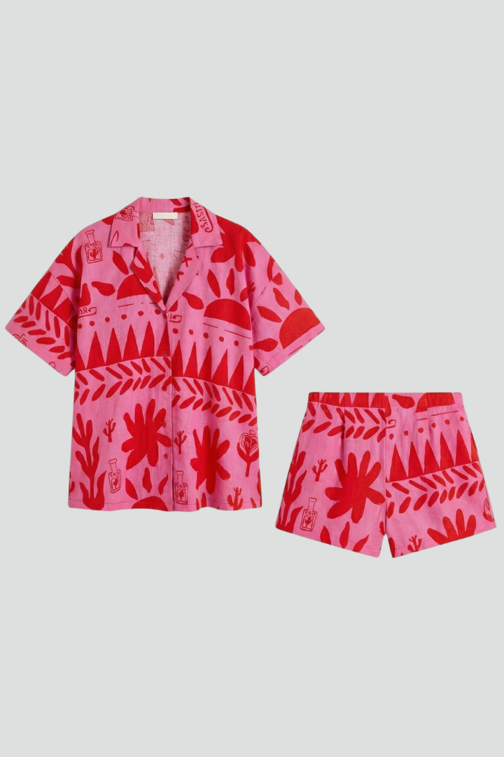 Women's pink tropical print camp collar shirt & high-waisted shorts co-ord set for summer vacation.