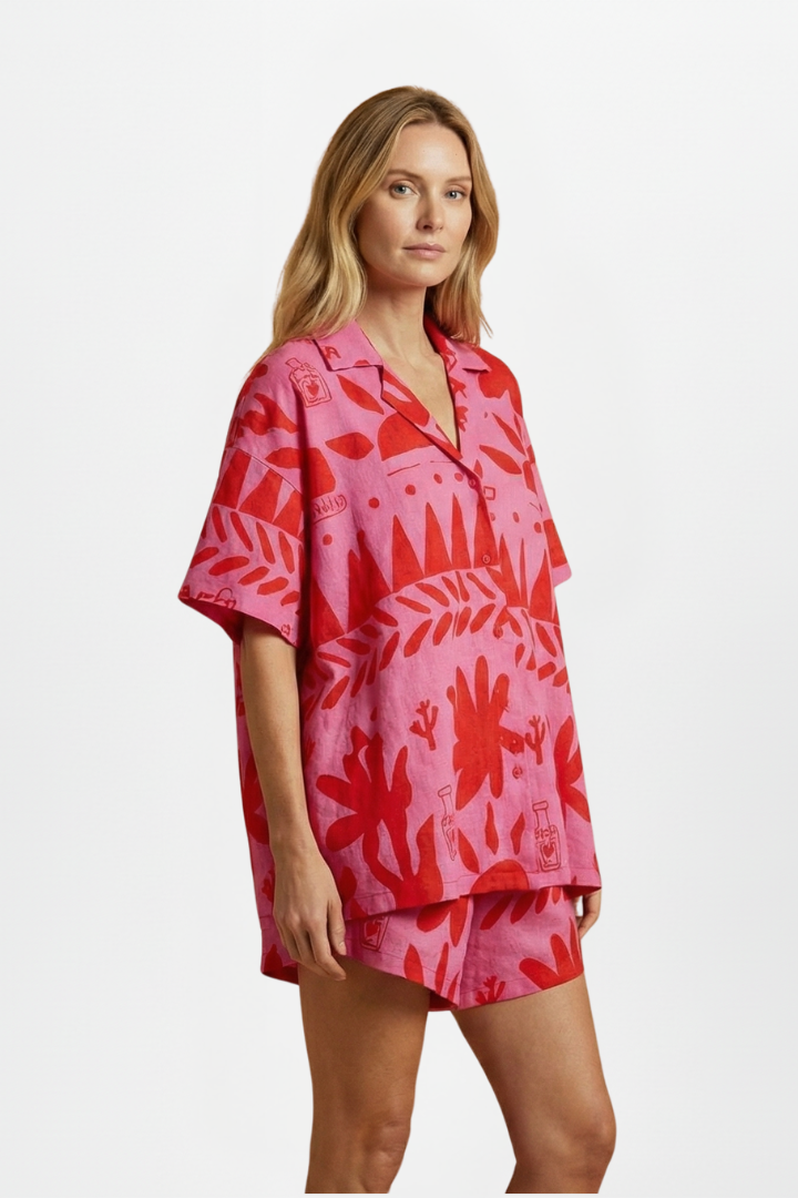 Vibrant pink tropical print women's vacation wear: relaxed fit camp collar shirt and high-waisted shorts set.