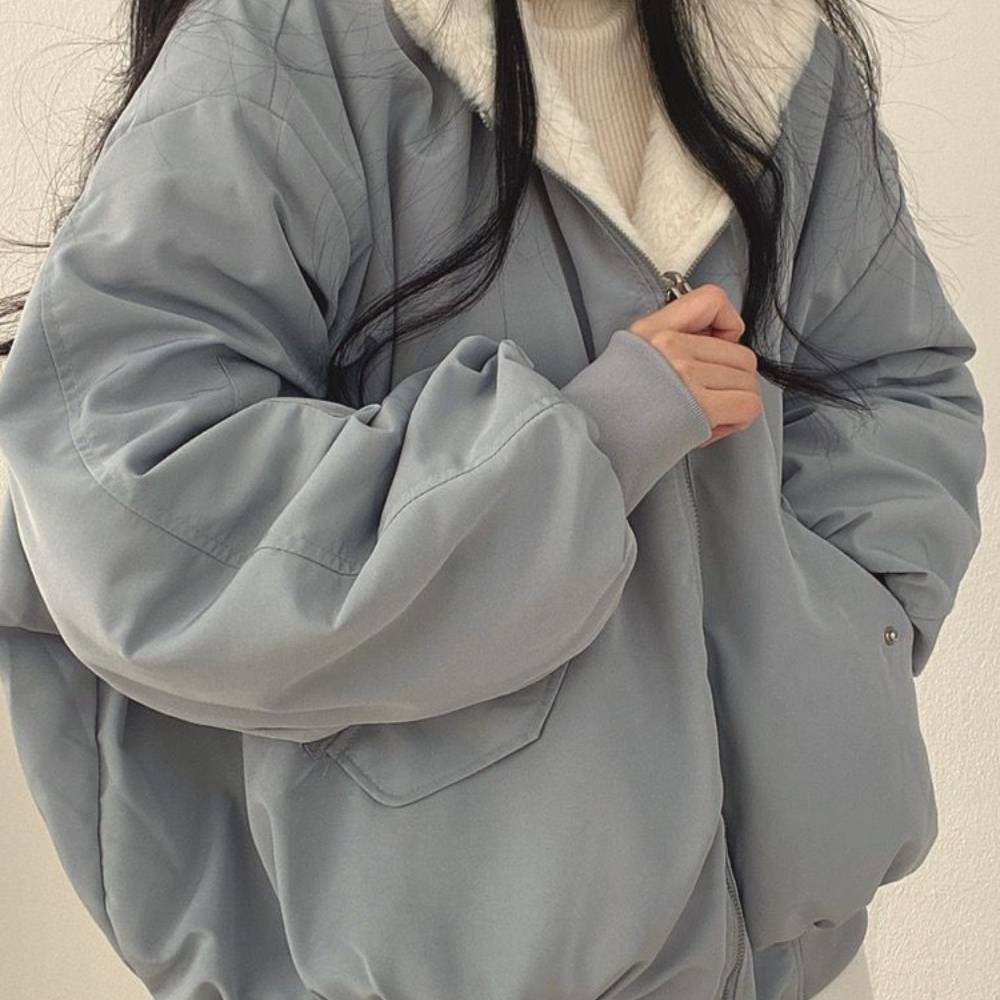 Model wears versatile women's reversible hooded jacket, showcasing cozy winter style.
