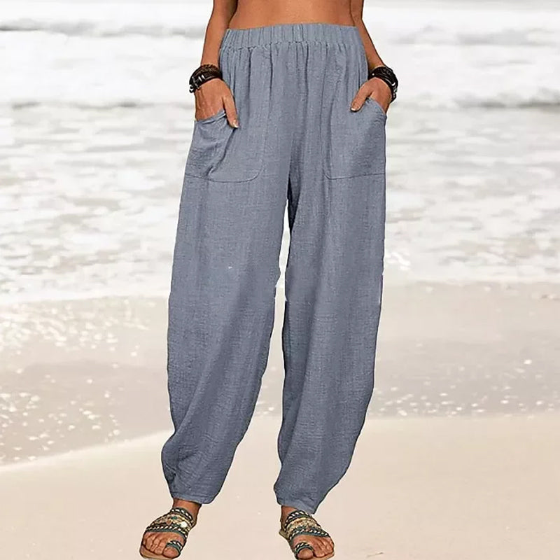 Model walks in flowy Rizza women's relaxed fit beach pants, showcasing their wide leg and vacation style.