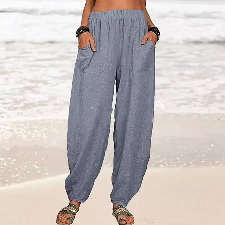 Model walks in flowy Rizza women's relaxed fit beach pants, showcasing their wide leg and vacation style.