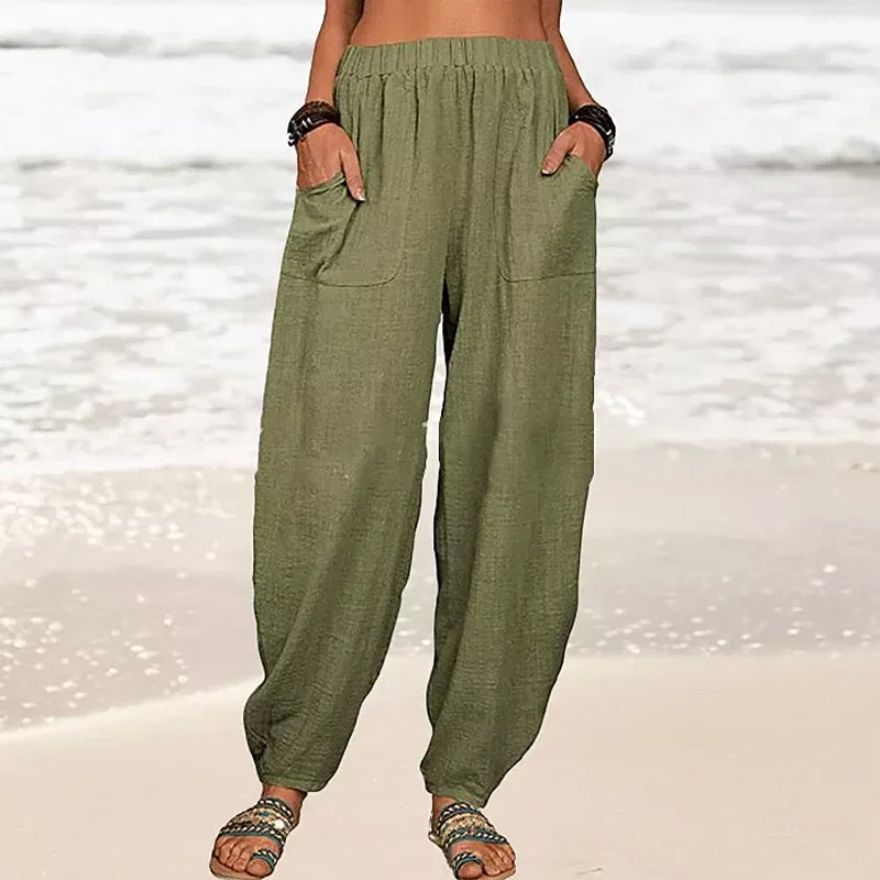 Women's Rizza relaxed fit beach pants worn on a sandy beach, perfect for travel, comfort, and summer fashion.