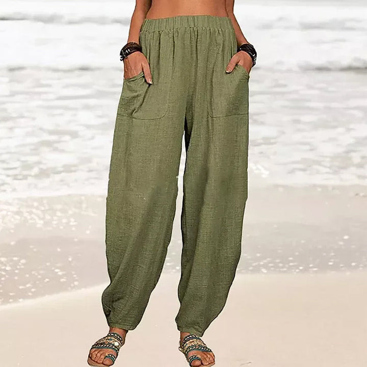 Women's Rizza relaxed fit beach pants worn on a sandy beach, perfect for travel, comfort, and summer fashion.