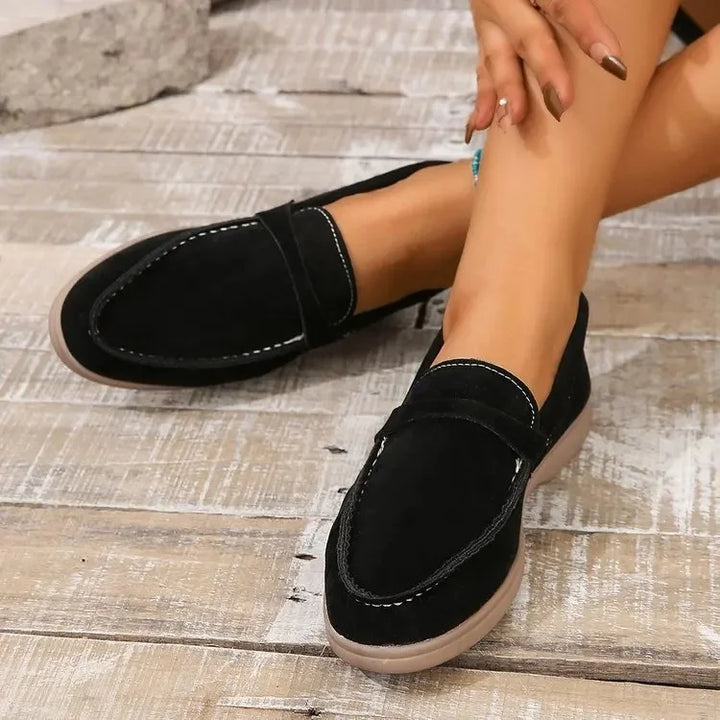 Woman wearing cushioned slip-on loafers in an office, emphasizing comfort for professional & casual look.