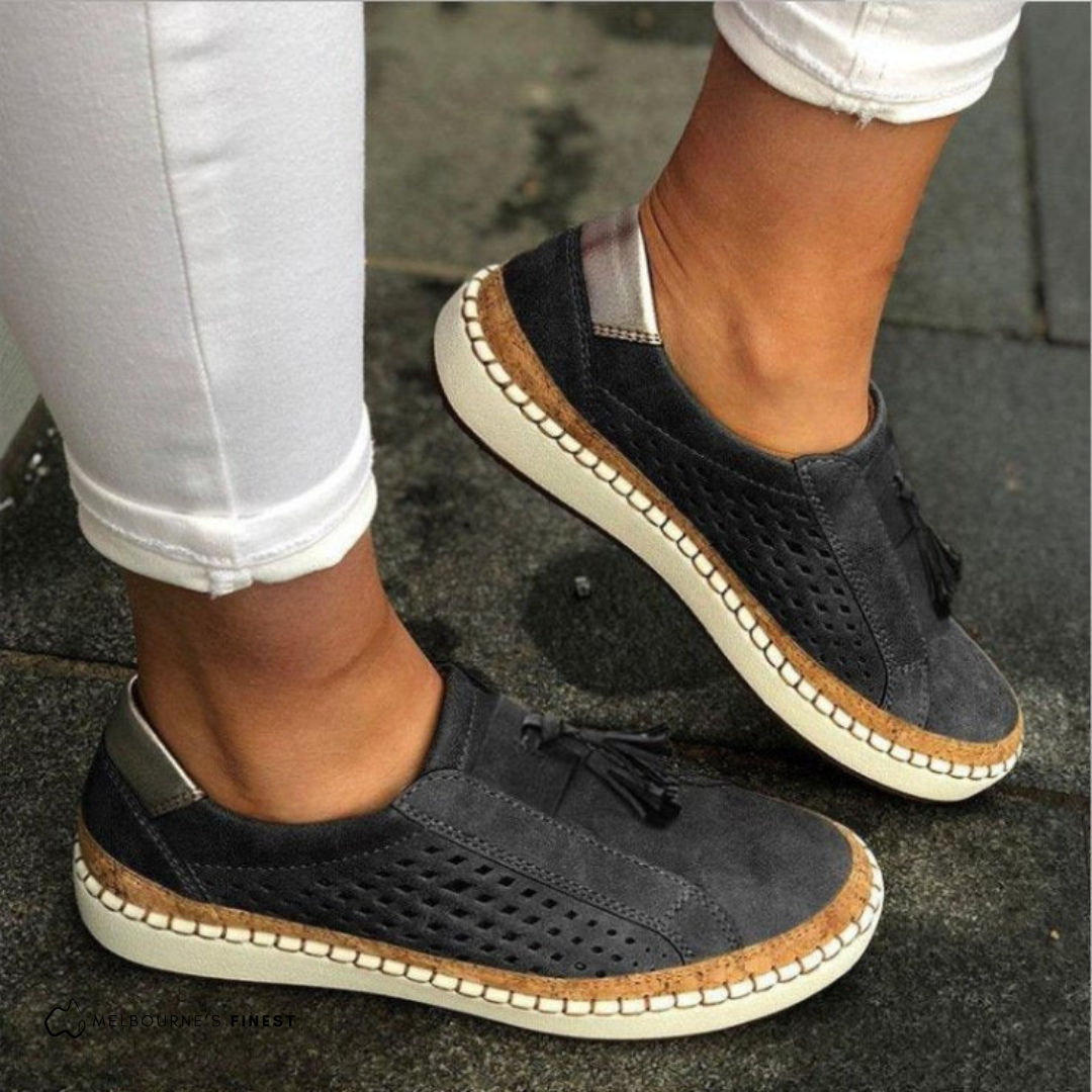 Close-up of women's perforated slip-on loafers featuring elegant tassel details. Casual & comfortable flat shoes.
