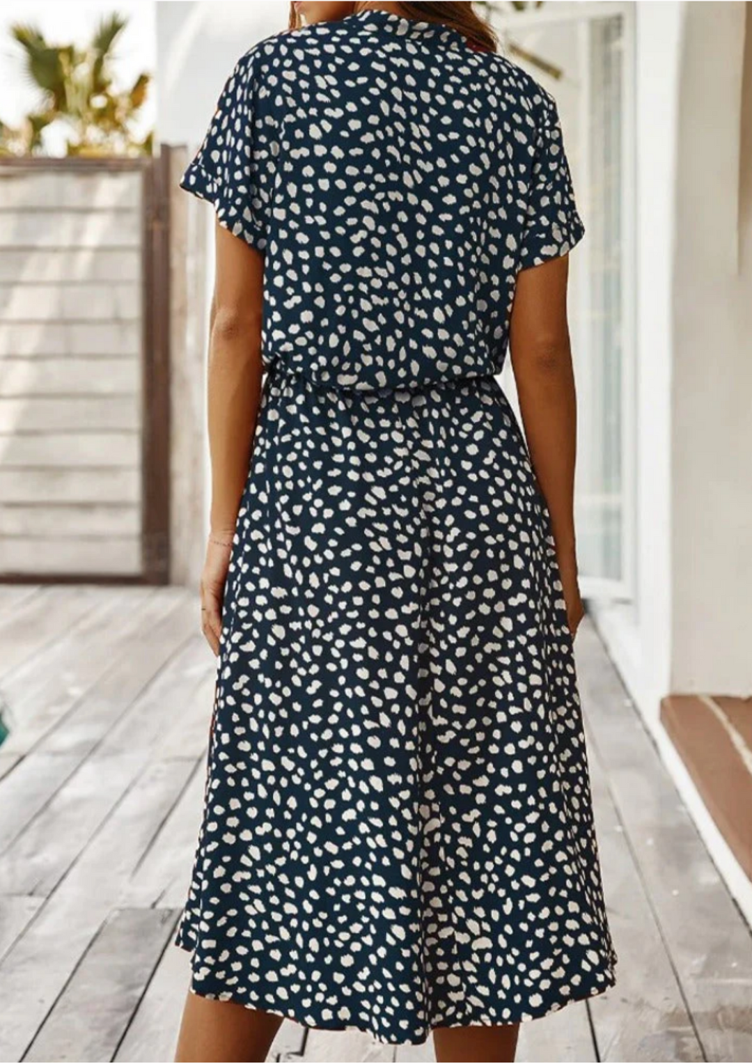 Women's elegant spotted midi dress featuring a V-neck, button-down detail, and a relaxed, flowy silhouette.