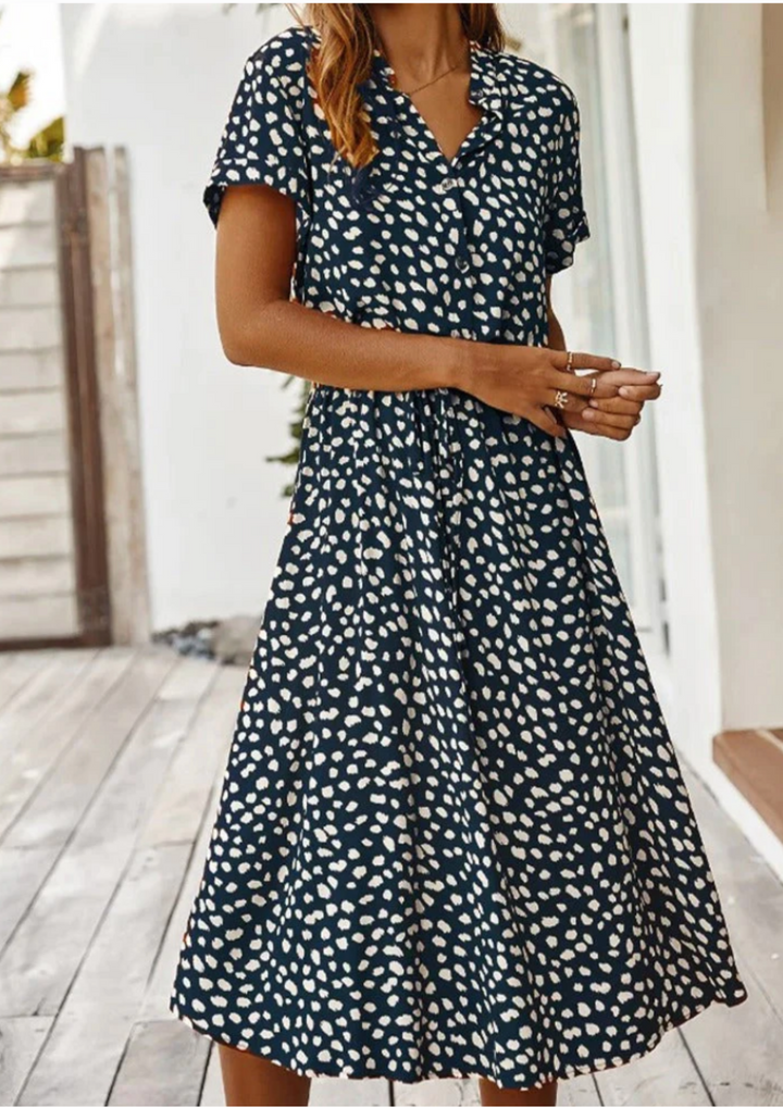 Stylish V-neck midi dress for women, with all-over spotted print and functional button-down front. Spring fashion.