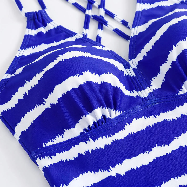 Low-rise black bikini bottoms complementing a striped tankini top. Stylish two-piece women's swimwear for beach/pool.
