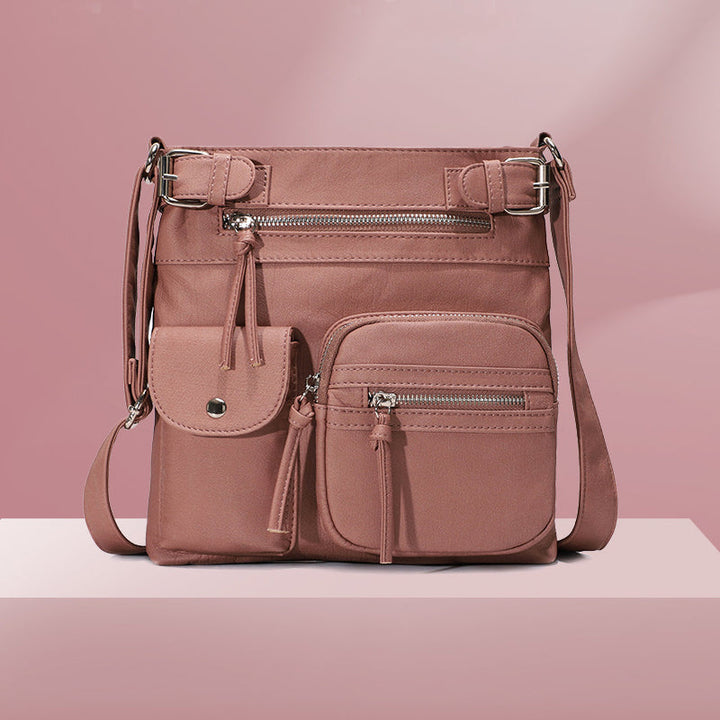 Front view of a women's anti-theft travel shoulder bag with multiple zippered pockets.