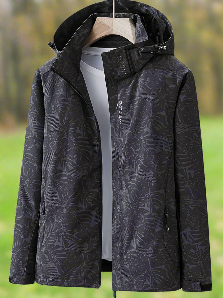 Active woman wearing lightweight waterproof rain jacket with leaf print, suitable for hiking & rainy summer days.