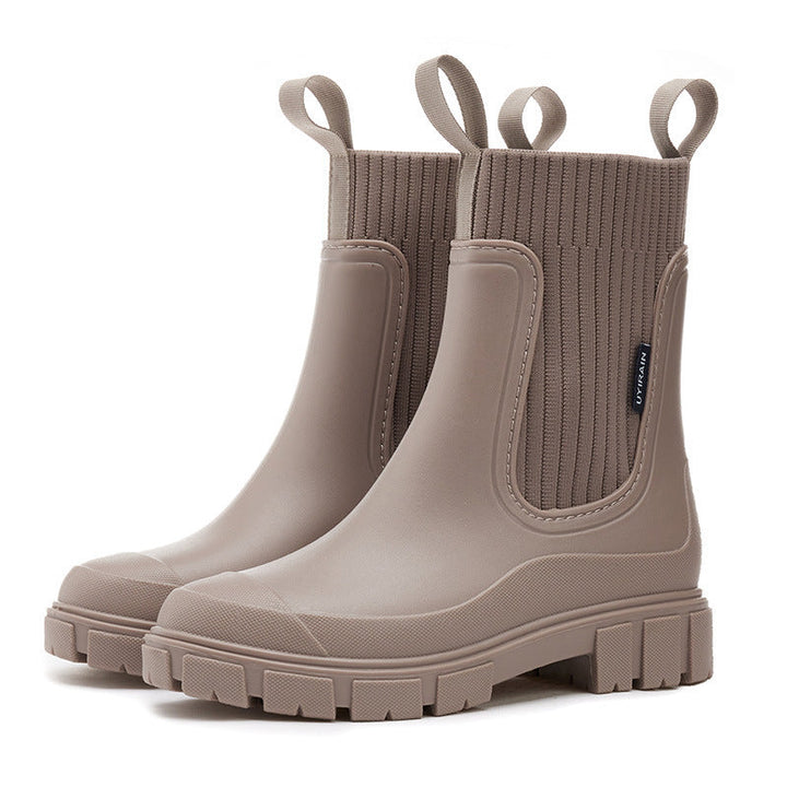 Stylish women wearing waterproof rain boots, walking confidently on a wet street. Ideal casual outdoor footwear.