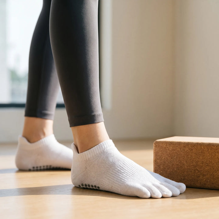 Women's white five-toe grip yoga socks for enhanced balance during pilates & barre workouts. Non-slip design.