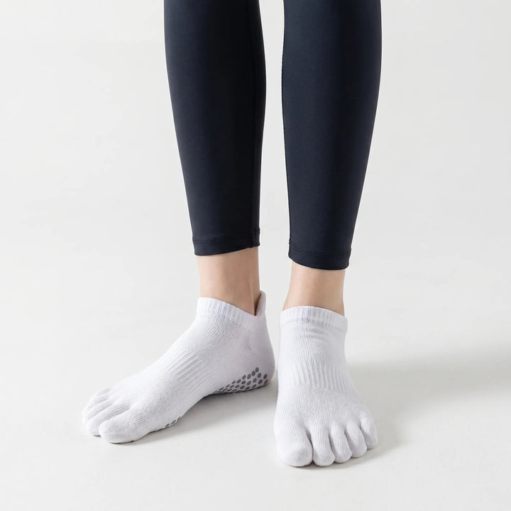 Low-cut white women's five-toe yoga socks, perfect for studio fitness, pilates, and barre. Enhanced grip activewear.