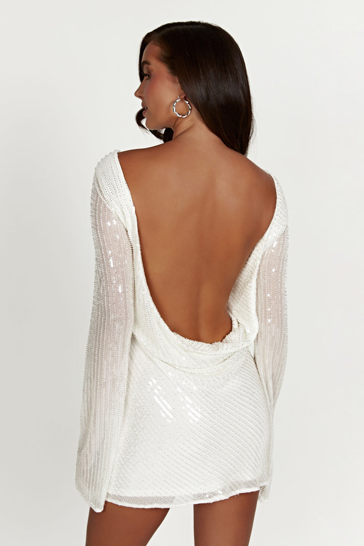 Model wearing a women's white sequin mini dress, showing off its shimmering fabric & elegant cut.