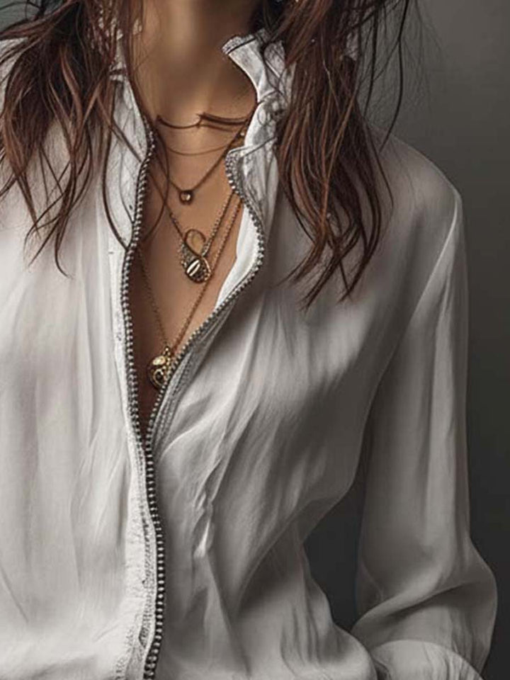 Professional white women's zip-front blouse, long sleeves, and sophisticated bell cuffs; modern workwear.