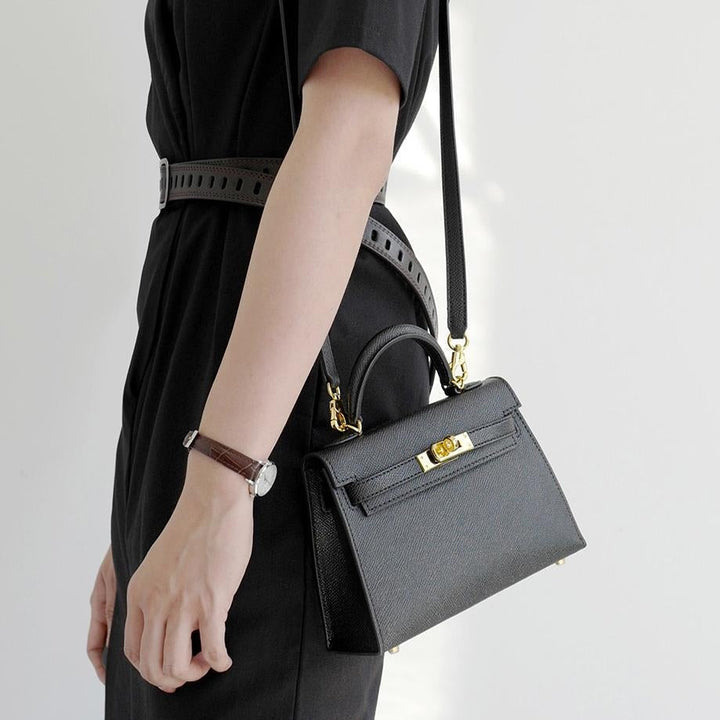 Elegant women's structured top handle crossbody bag with a sleek turn lock closure. Versatile fashion accessory.