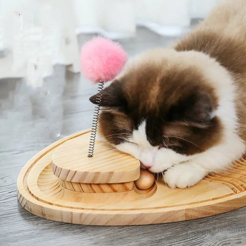 Cat sharpening claws on a wooden scratching board, engaged with the interactive feather toy